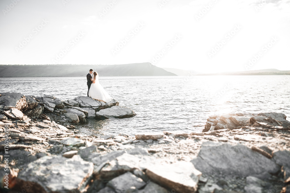 Happy and romantic scene of just married young wedding couple posing on beautiful beach