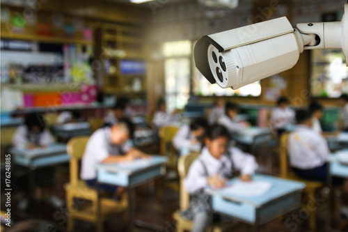 CCTV monitoring, security cameras in a classroom against blur primary students doing examination background
