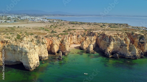 Aerial shot taken with drone of panoramic view with rocky cliffs of coastline and city placed above on hills and shoreline, Portugal, Algarve.