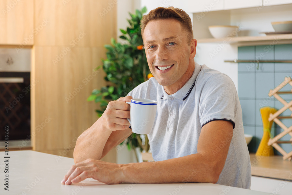 Joyful positive man drinking tea