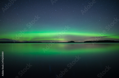 Northern lights dancing over calm lake. Farnebofjarden national park in Sweden. © Conny Sjostrom