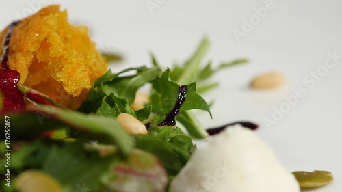 Italian Roast Beet Salad. Salad of roasted beets with goat cheese and pine nuts on white dish isolated on a white background. Tagliatelle with beet and cheese on plate, soft focus photo
