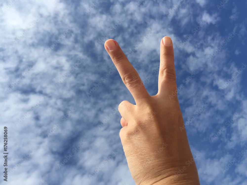 hand making victory sign against blue sky hand making victory sign against blue sky