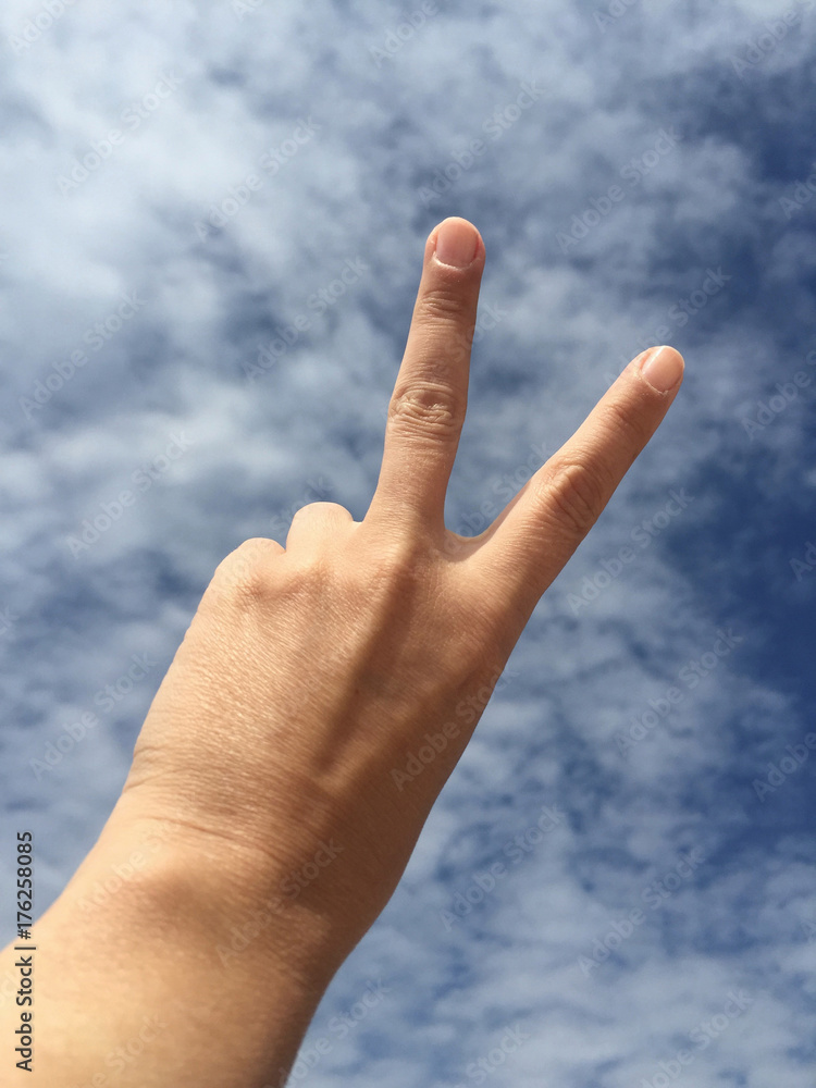hand making victory sign against blue sky hand making victory sign against blue sky