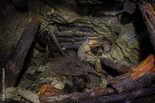 Underground abandoned ore mine shaft tunnel gallery passage with wooden timbering