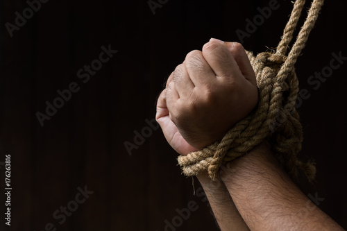 Hands are tied with rope On the black background / loss of freedom and human rights