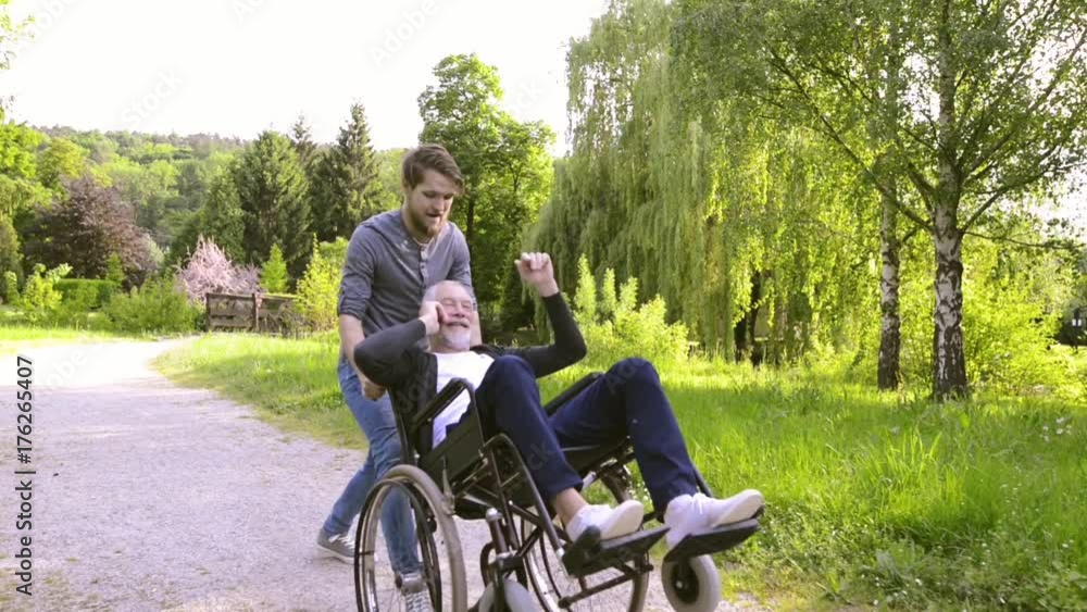 Son with disabled father in wheelchair in the park. Son with disabled father in wheelchair in the park.