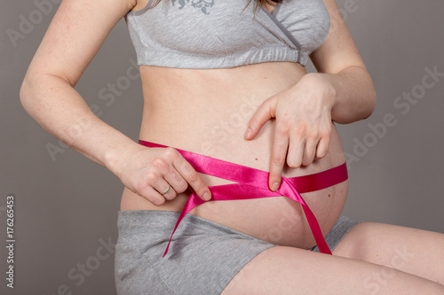 pregnant belly on neutral grey background