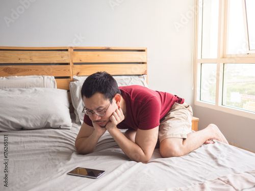 Lonely man playing his phone in his bedroom. photo