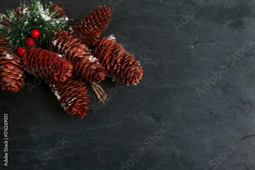 Pine cones and festive leaves on slate background