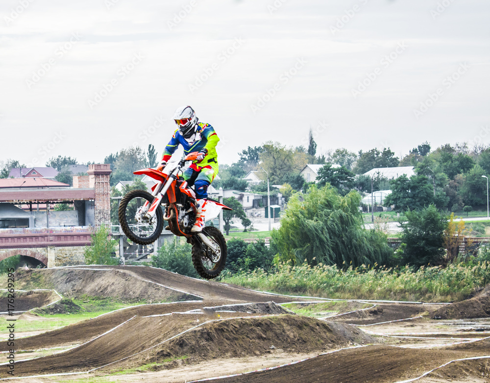 The racer on a motorcycle participates in a motocross race, jumps on a springboard. He took off high on a motorcycle.