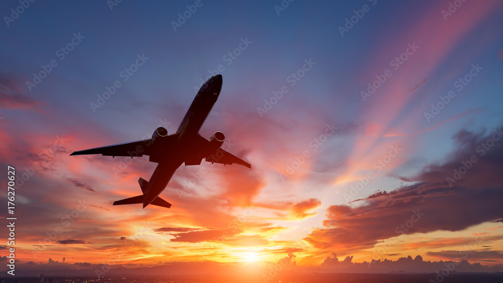 Obraz premium Sylwetka samolotu pasażerskiego lecącego w zachód słońca.