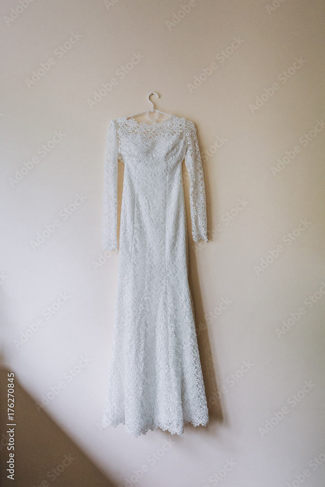Wedding dress covered with laces hangs on the wall
