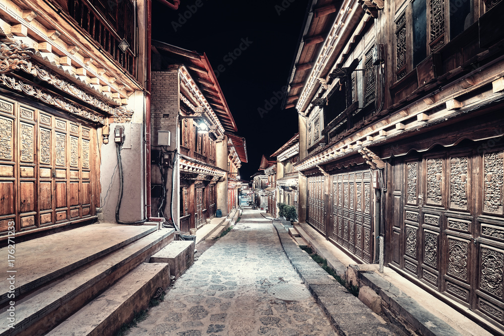 Vintage toned picture of illuminated empty street of Shangri La Old Town (Dukezong) at night, China.