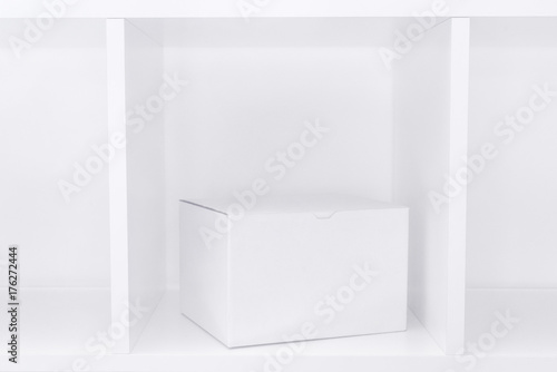 White cardboard box on wooden shelf as copy space