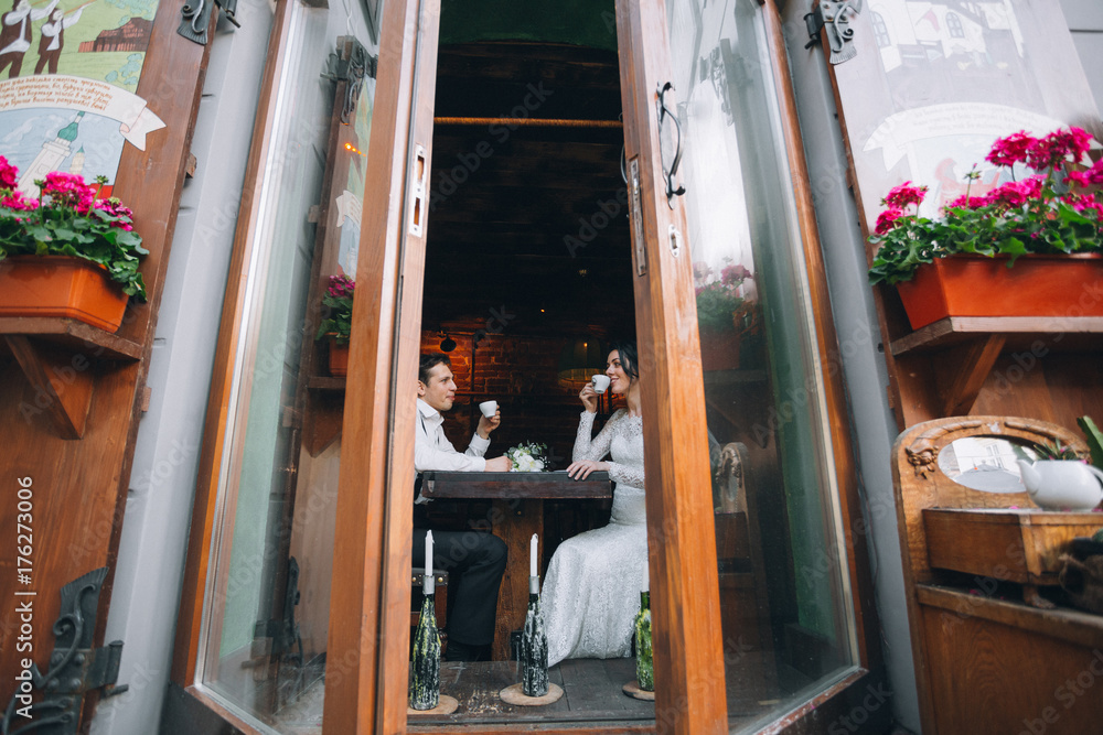 Wedding couple drinks coffee sitting at the table in a cafe Wedding couple drinks coffee sitting at the table in a cafe