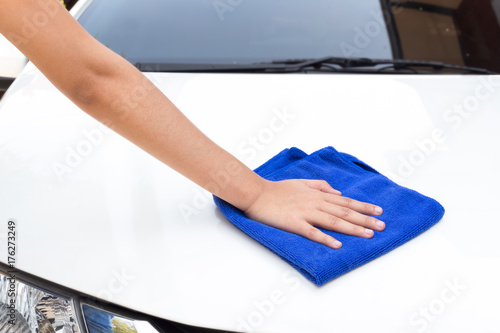 Woman hands cleaning white car using microfiber cloth.