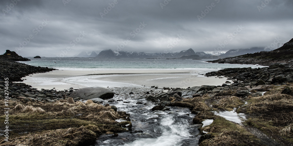 A river flows into the wild sea on the coast of the Lofoten Islands