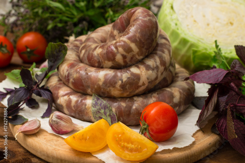 Raw fresh sausages in a white plate on a wooden background. Top view. Close-up