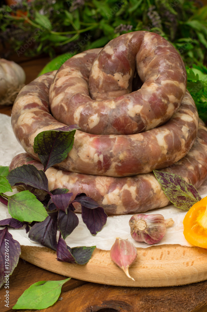 Raw fresh sausages in a white plate on a wooden background. Top view. Close-up Raw fresh sausages in a white plate on a wooden background. Top view. Close-up