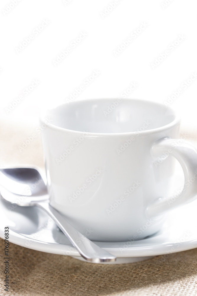 White ceramic cup on a linen tablecloth White ceramic cup on a linen tablecloth