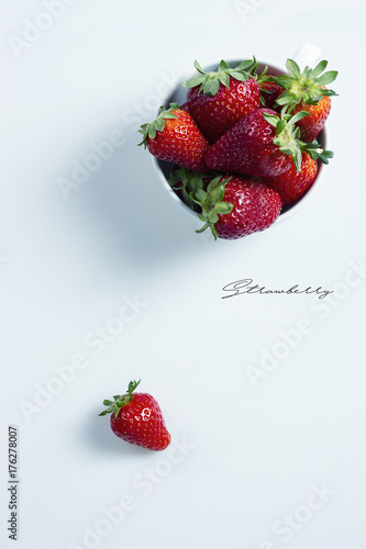 Strawberries in a white bowl on a white table with copyspace