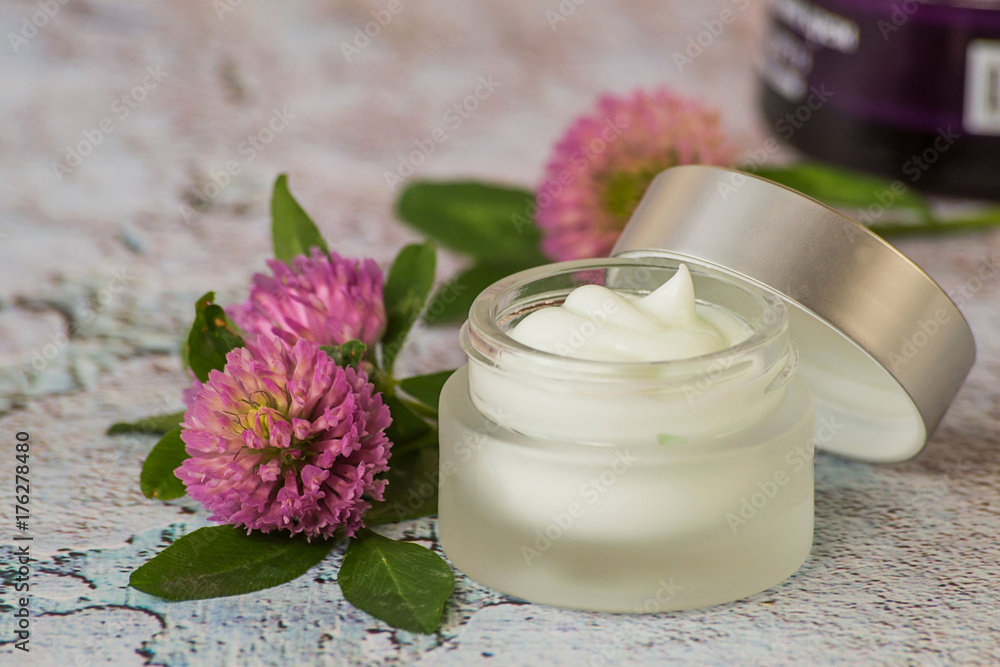 Natural cosmetic. A small glass jar with cream for skin care face and fresh clover flowers on a light background. Natural cosmetic. A small glass jar with cream for skin care face and fresh clover flowers on a light background.