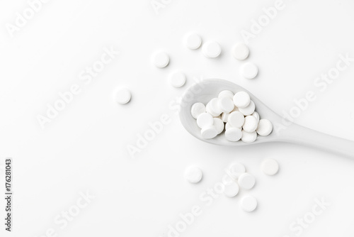 Pills on the spoon and scattered on the white surface