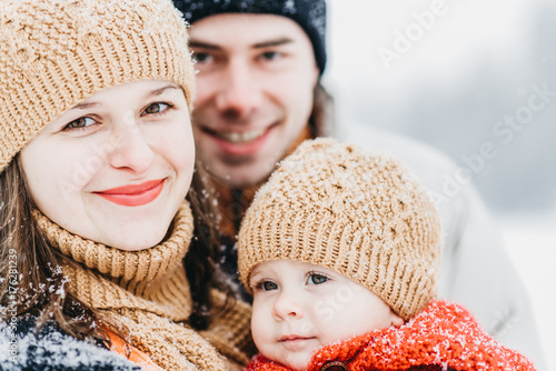 Cute family playing in the park in winter