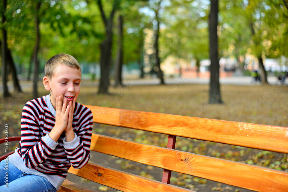 The young guy sits on a bench in park The young guy sits on a bench in park