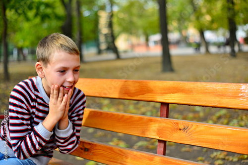 The young guy sits on a bench in park