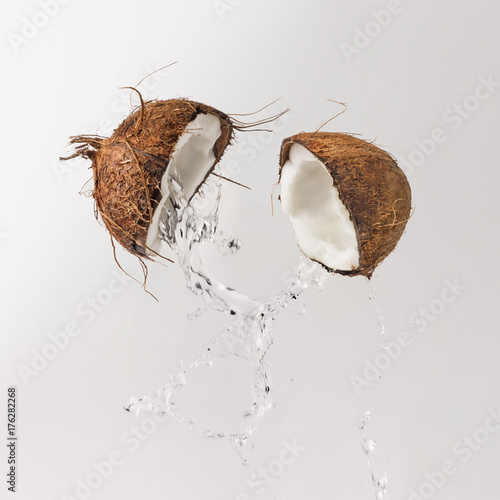 Fototapeta Cracked coconut with water splash. Summer tropical concept.
