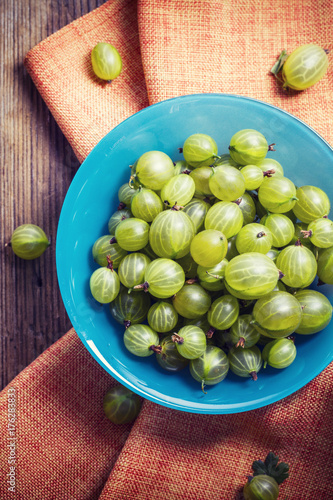 Fresh gooseberries in a blue bowl, view from top