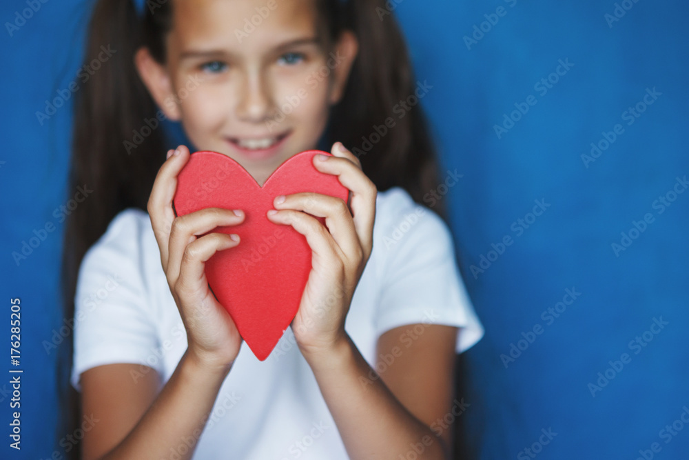 smiling little girl with red heart in hands on blue background smiling little girl with red heart in hands on blue background