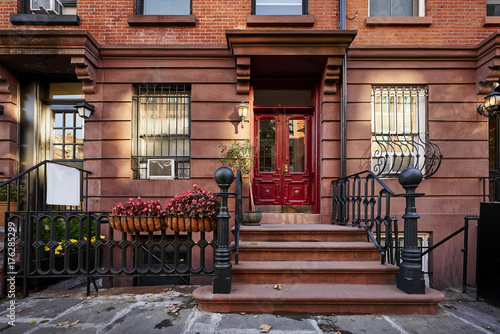 a red door on a brownstone building © goodmanphoto