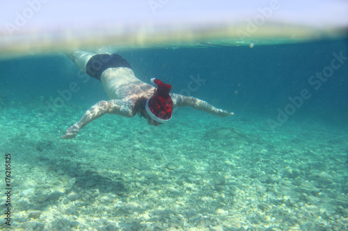 Man in Santa hat swimming underwater photo