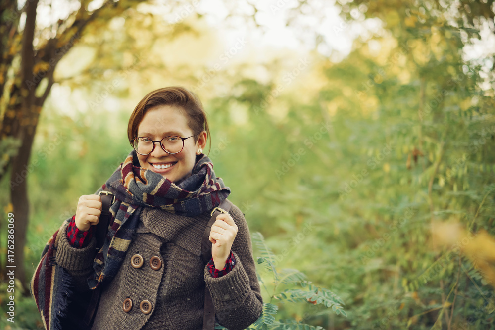 Portrait happy beautiful young girl with glasses and with a big smile in the autumn park. fashion and coziness in autumn.