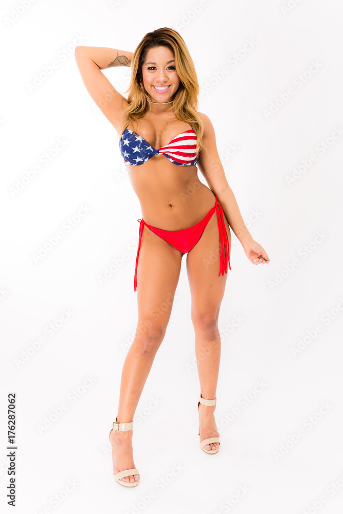 Young fit hispanic woman in American Flag patterned swimsuit posing on a white background Young fit hispanic woman in American Flag patterned swimsuit posing on a white background
