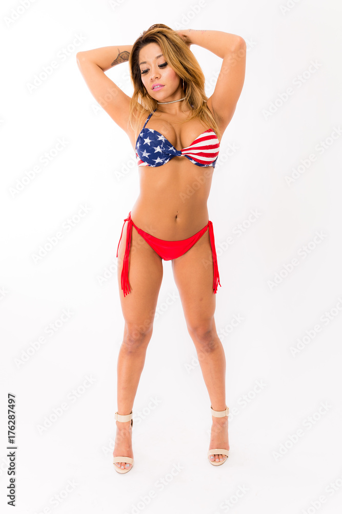 Young fit hispanic woman in American Flag patterned swimsuit posing on a white background Young fit hispanic woman in American Flag patterned swimsuit posing on a white background