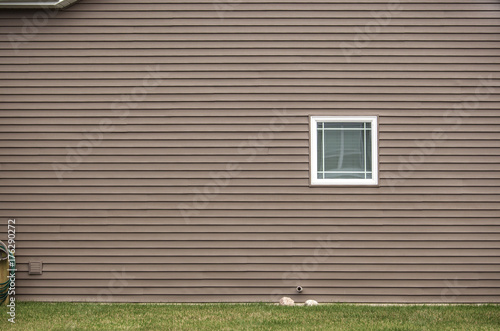 Contemporary tan colored vinyl siding with window photo