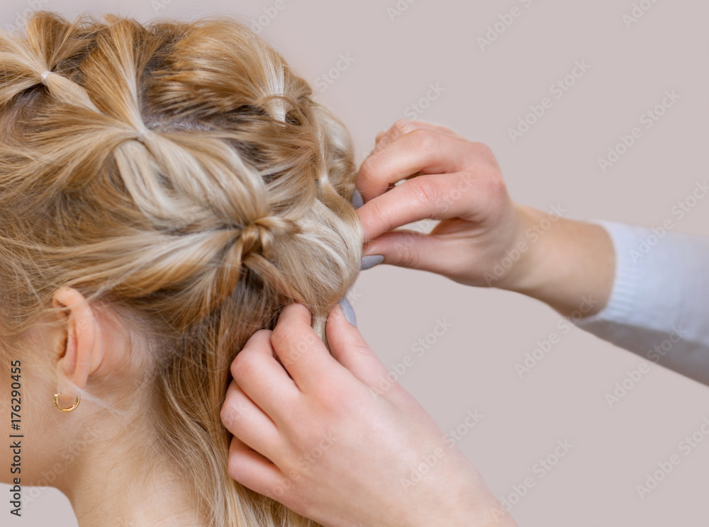 Fototapeta premium Beautiful blonde girl with a beautiful, neat hairstyle, close-up in a beauty salon. Professional hair care and creating hairstyles.