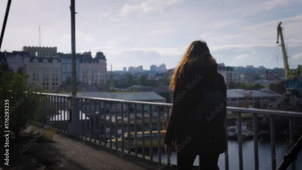 The young girl is strolling through the abandoned bridge observing the old harbour The young girl is strolling through the abandoned bridge observing the old harbour