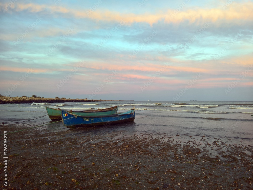 Naklejka premium Fishing boats at seaside under colorful sunset 