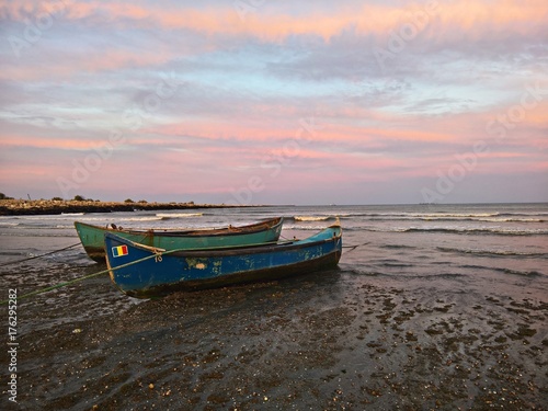 Fishing boats at seaside under colorful sunset 