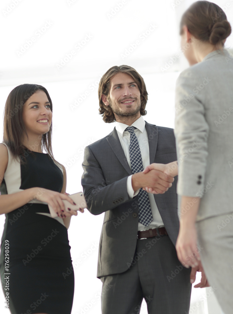 Businesspeople shaking hands against room with large window loo Businesspeople shaking hands against room with large window loo