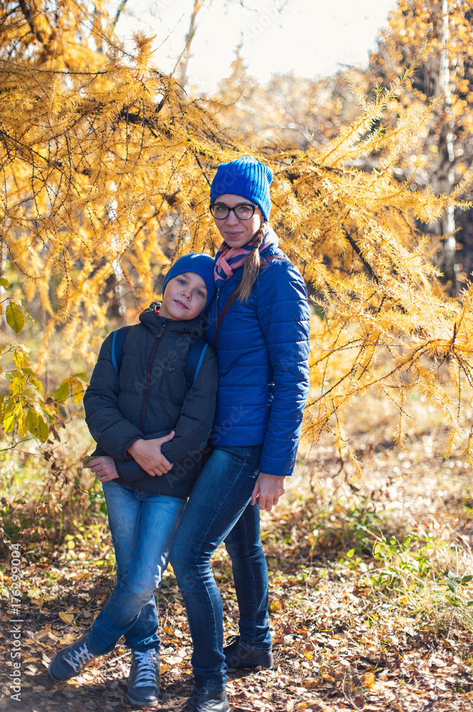 Mother and son at autumn park in sunny beauty day