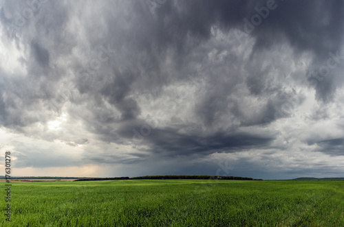 Dramatic storm scene with rain at the horizon and rural path going towards left