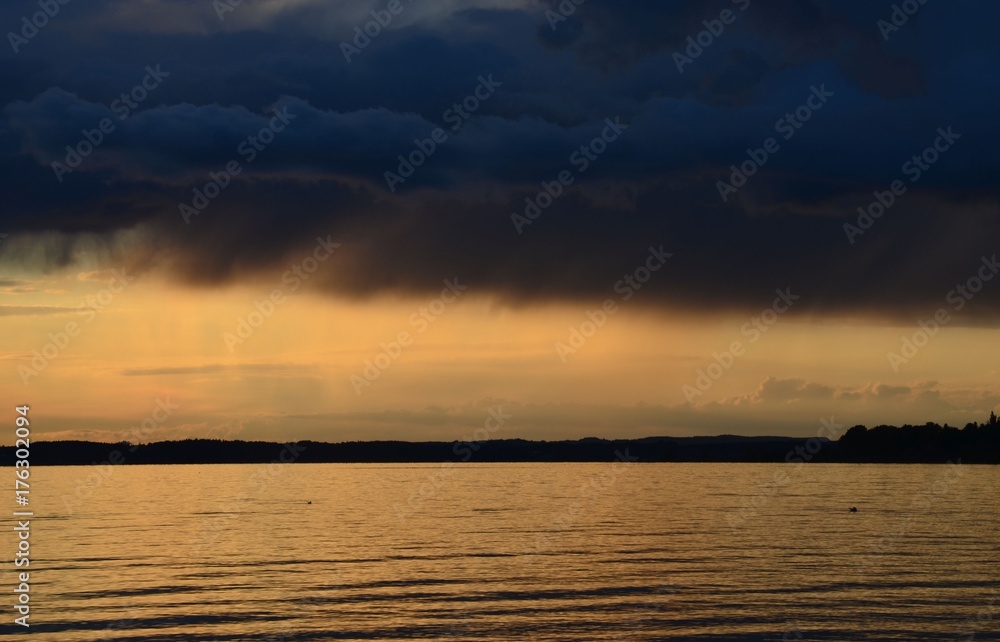 Bedrohlich schwarze Regenwolken über dem Chiemsee bei Sonnenuntergang