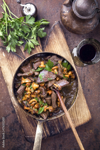 Fresh fried veal liver with chanterelle and baguette in sauce as top view in a casserole photo