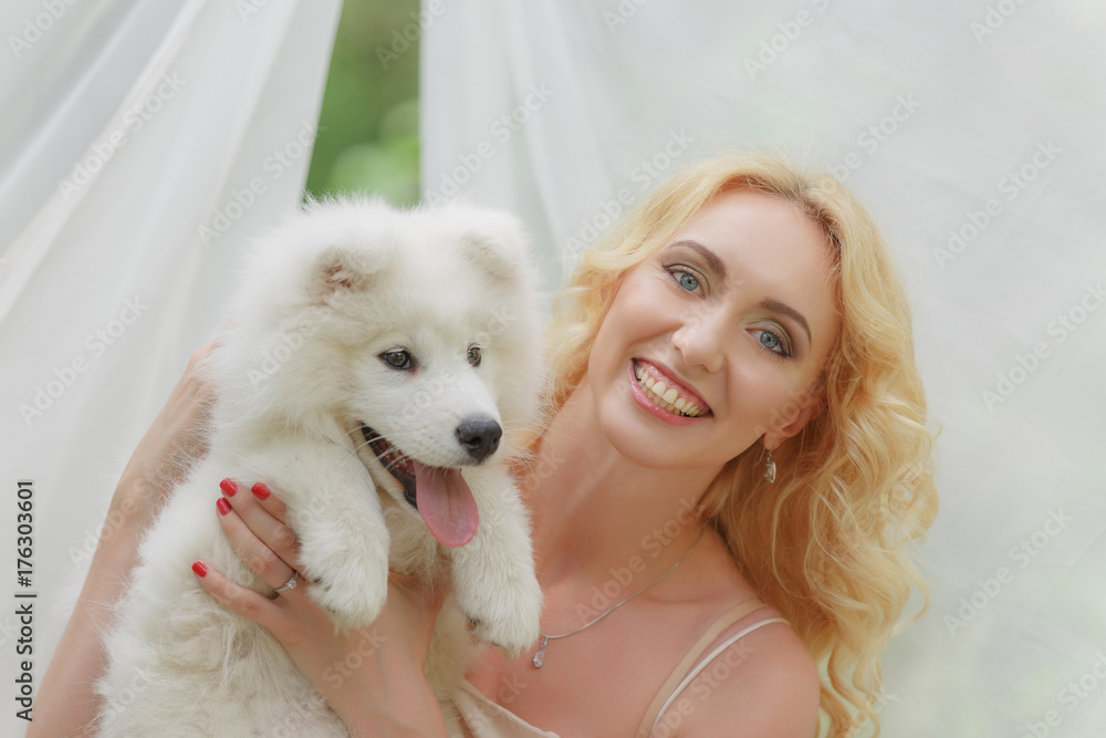 blond girl sitting on the street with a white dog in her arms blond girl sitting on the street with a white dog in her arms